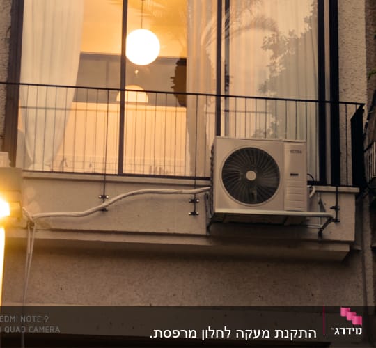 מסגרת חלון עם וילון ומזגן חיצוני